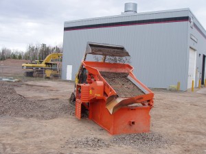 A ScreenKing Mini soil screener being fed by a skidsteer loader